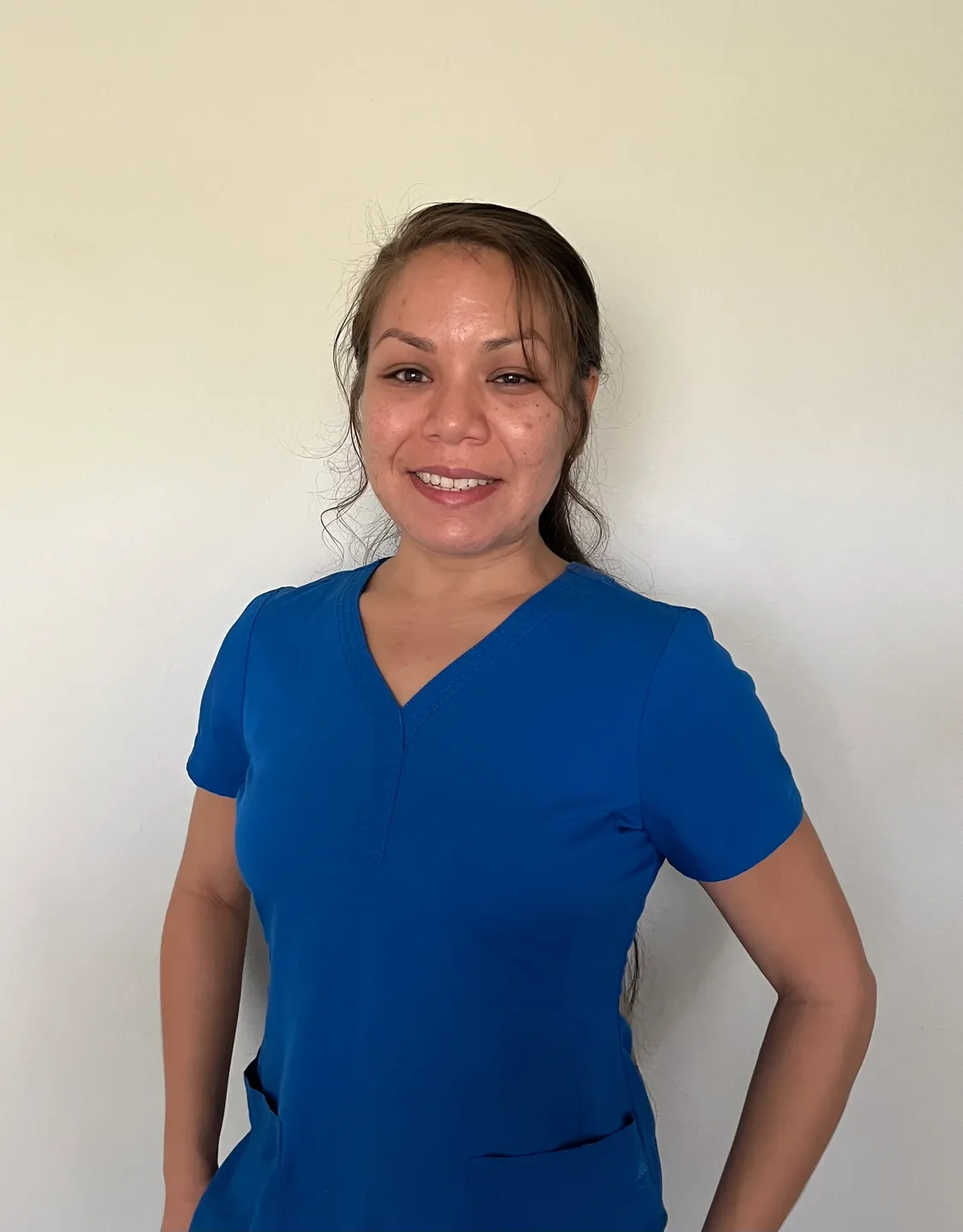 A woman in blue shirt standing next to wall.